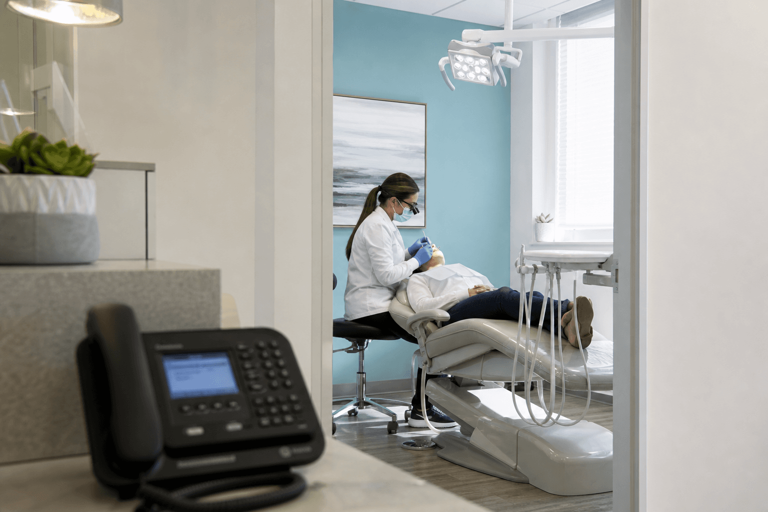 Dental treatment room in soft focus with a ringing phone at reception in the foreground